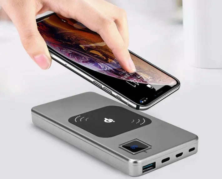 Black alloy power bank with LCD display showing battery percentage, next to a smartphone.