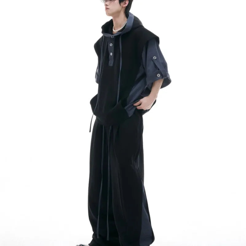 Man wearing a black hooded zip-up jacket and matching trousers from a heavy polyester tracksuit set.