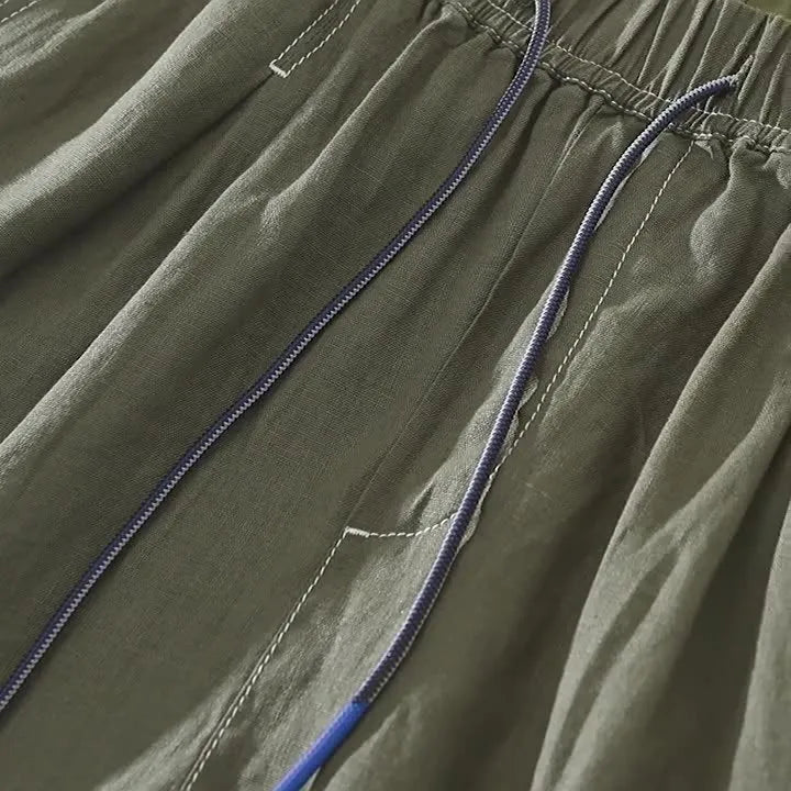Men's loose straight fit linen shorts in green with drawstring waist, shown laid flat