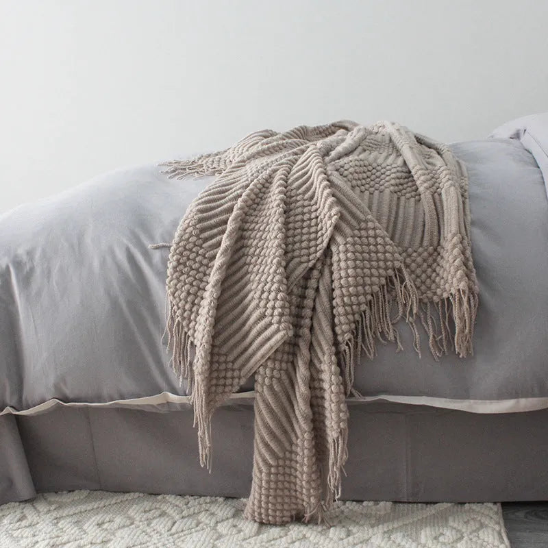 Small light grey polyester fleece throw blanket folded on a sofa.