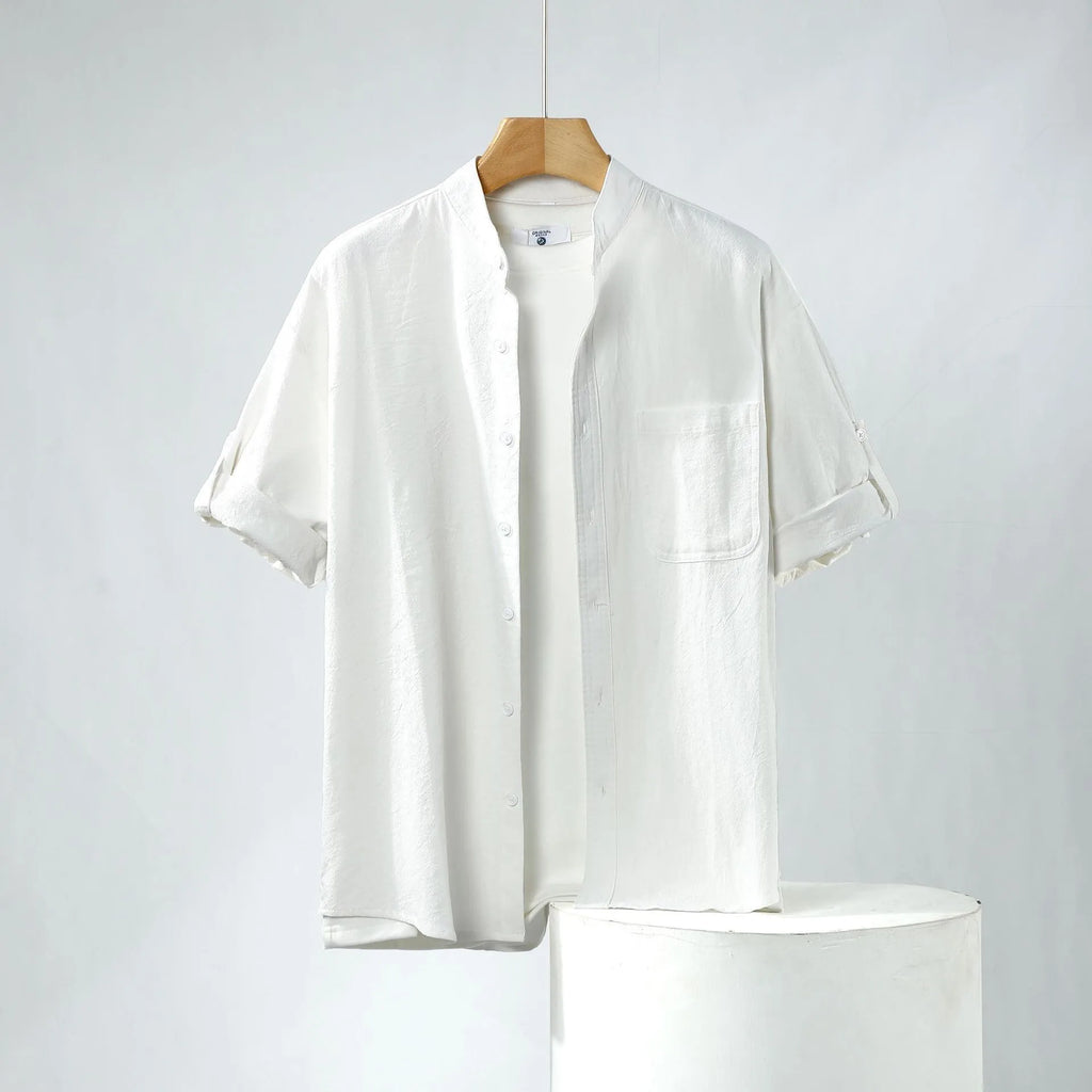 A man's loose-fitting, short-sleeved linen shirt in a solid colour with a stand collar.