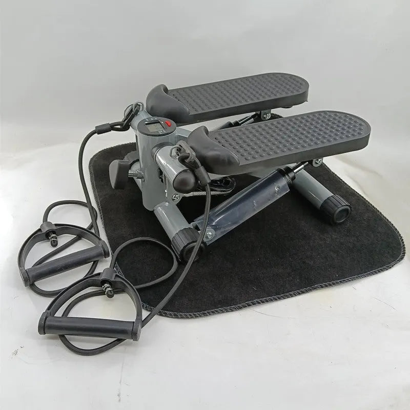 Silver grey hydraulic mini treadmill for waist slimming exercises in a home setting.