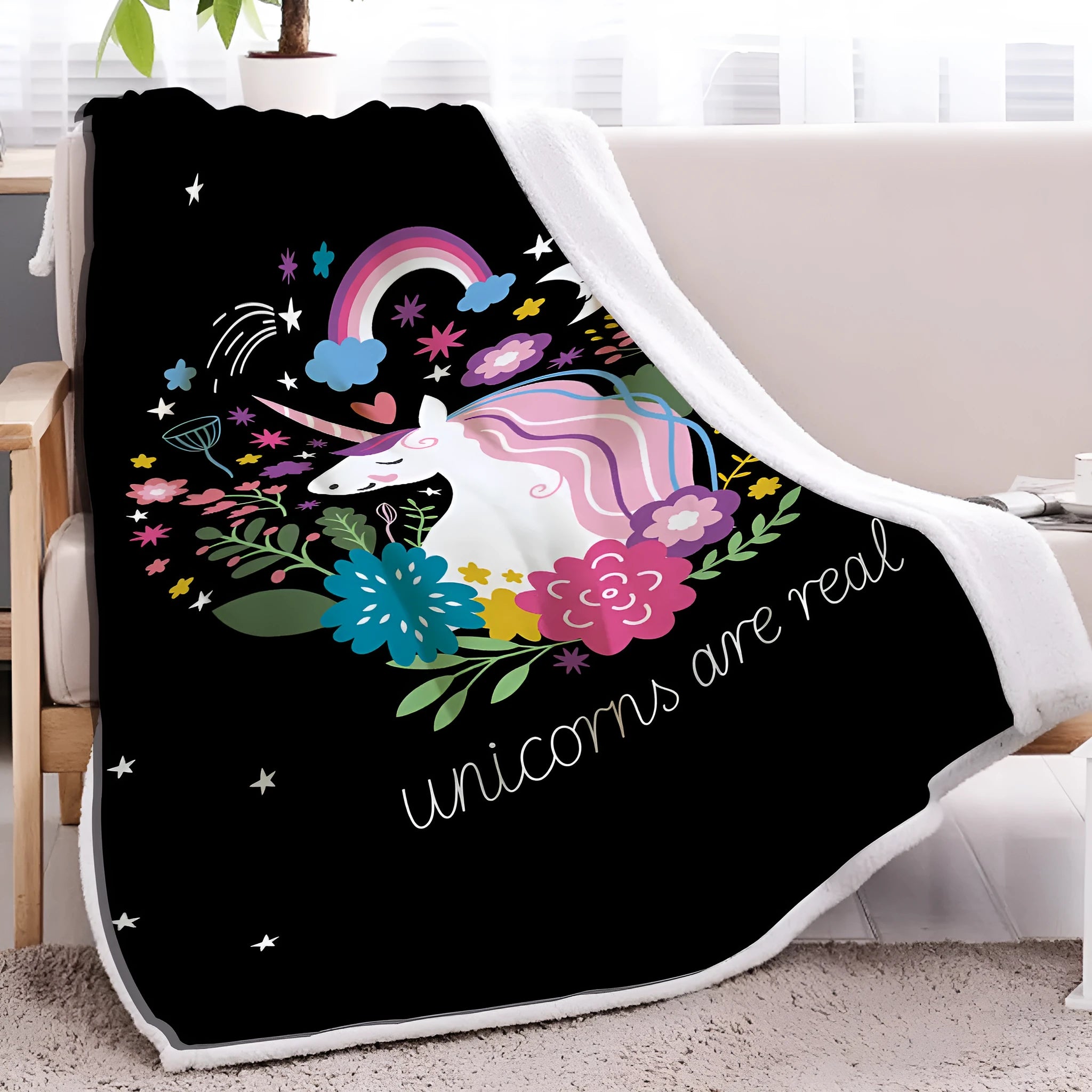 Black sherpa fleece blanket folded on a couch, soft fabric with hemmed edges.
