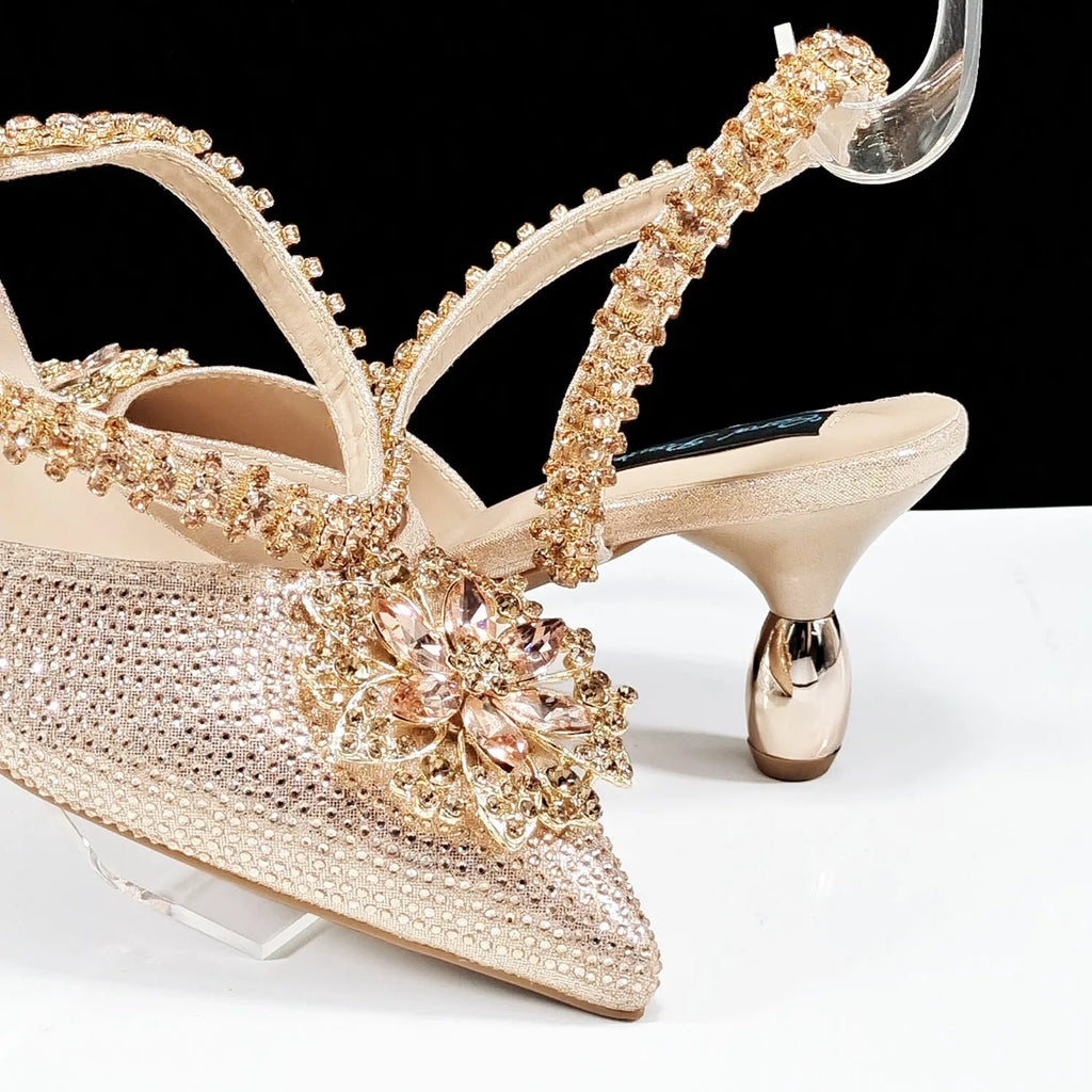Women's black high heel and clutch bag set with rhinestone ankle chain and floral metal decoration.