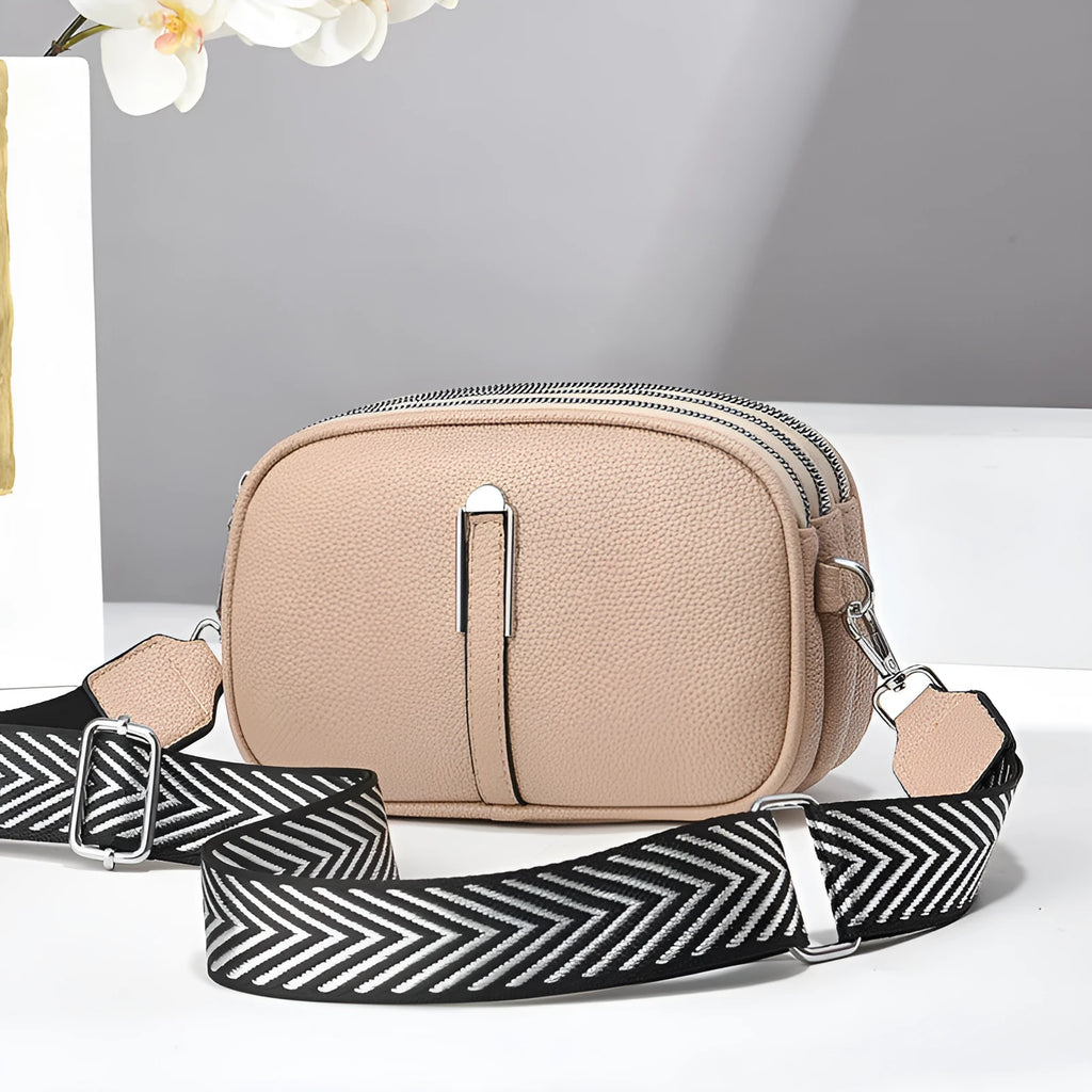 A soft oval-shaped women's crossbody bag in PU leather with a stone pattern texture and a front slit pocket.