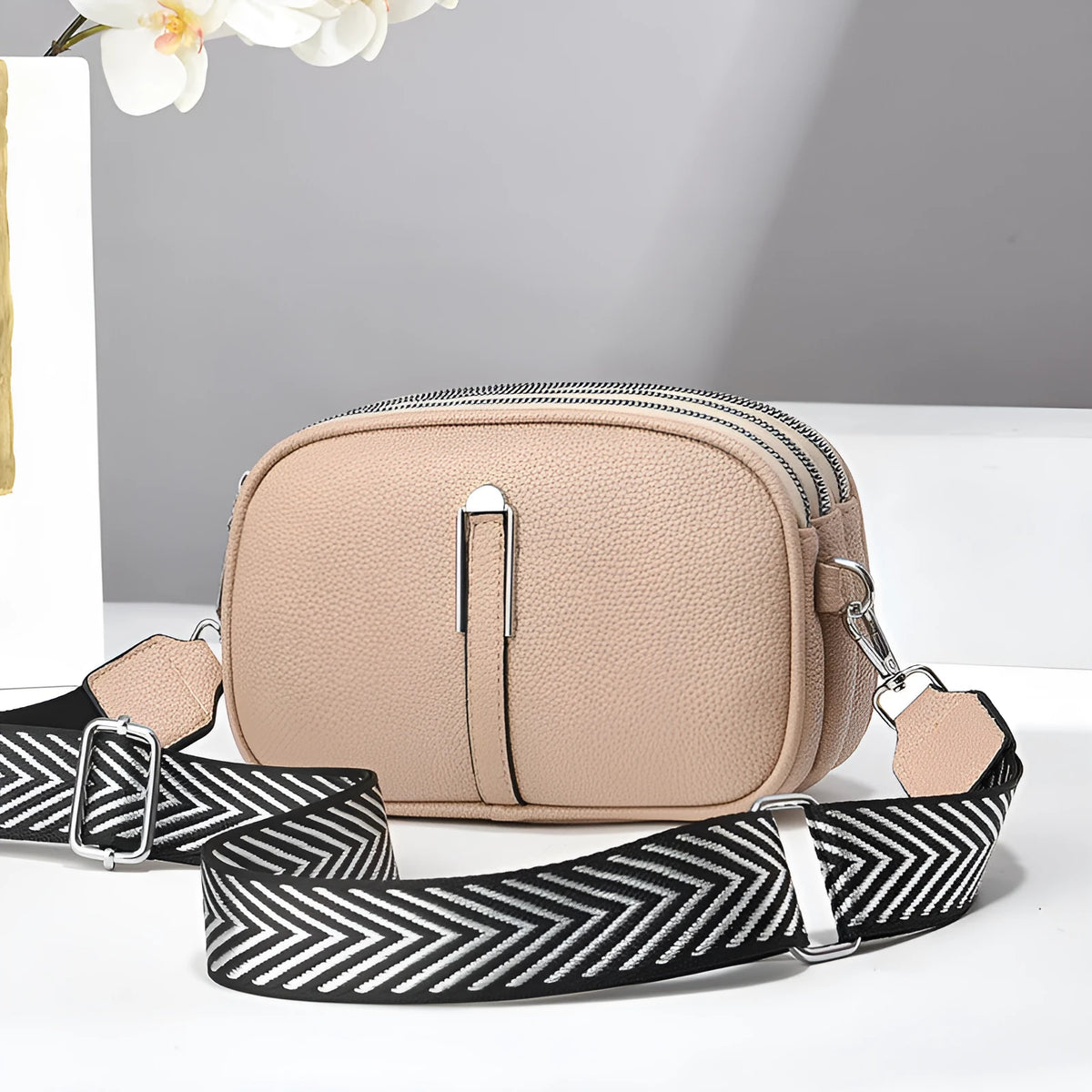 A soft oval-shaped women's crossbody bag in PU leather with a stone pattern texture and a front slit pocket.