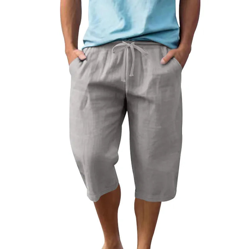 Man wearing loose, cropped linen shorts in a solid colour with a drawstring waist.