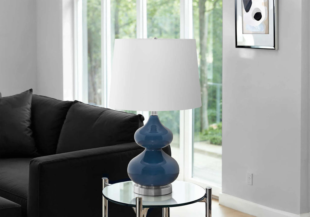 Blue crystal glass desk lamp with a white fabric shade on a wooden desk.