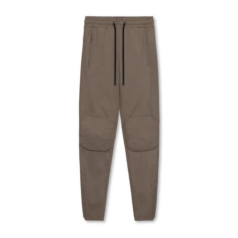 Men's loose grey fitness trousers with elasticated ankle ties on a gym floor.