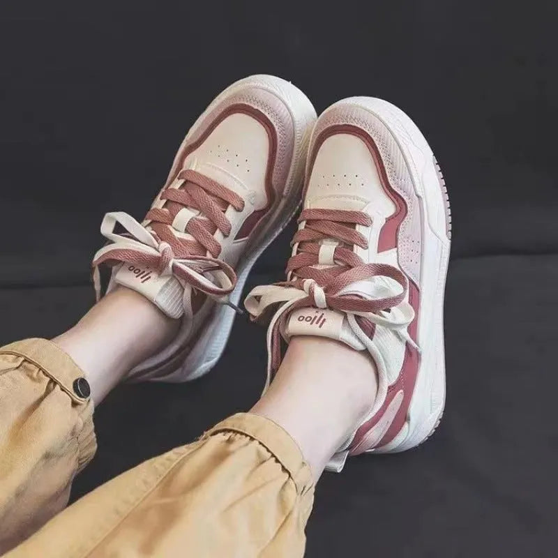 Pink and white low top women's sneakers with a rubber sole and height increasing feature.