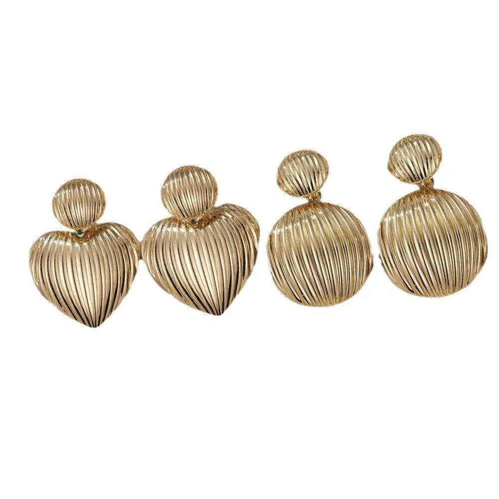 Gold alloy heart-shaped and round earrings for women on a plain background