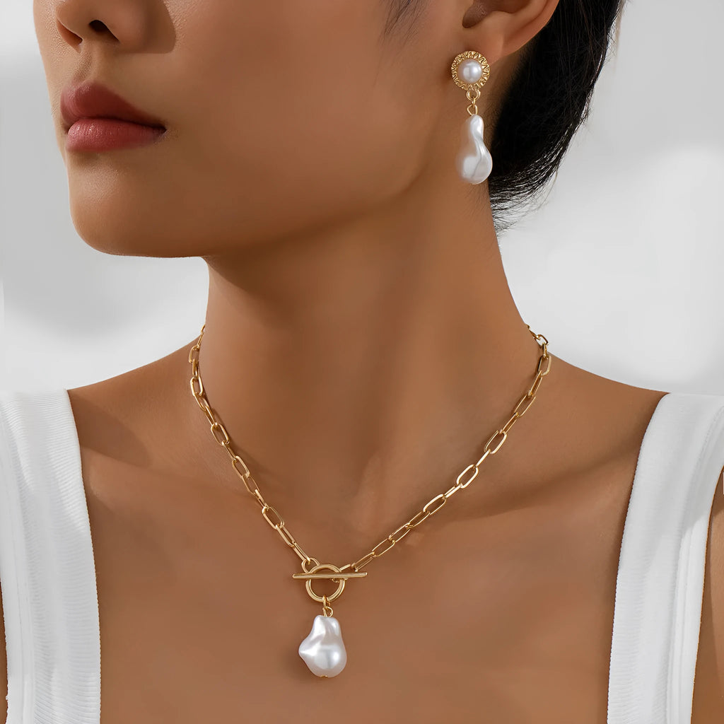 Gold tone retro style necklace and matching pearl ear studs set for women on a flat surface.