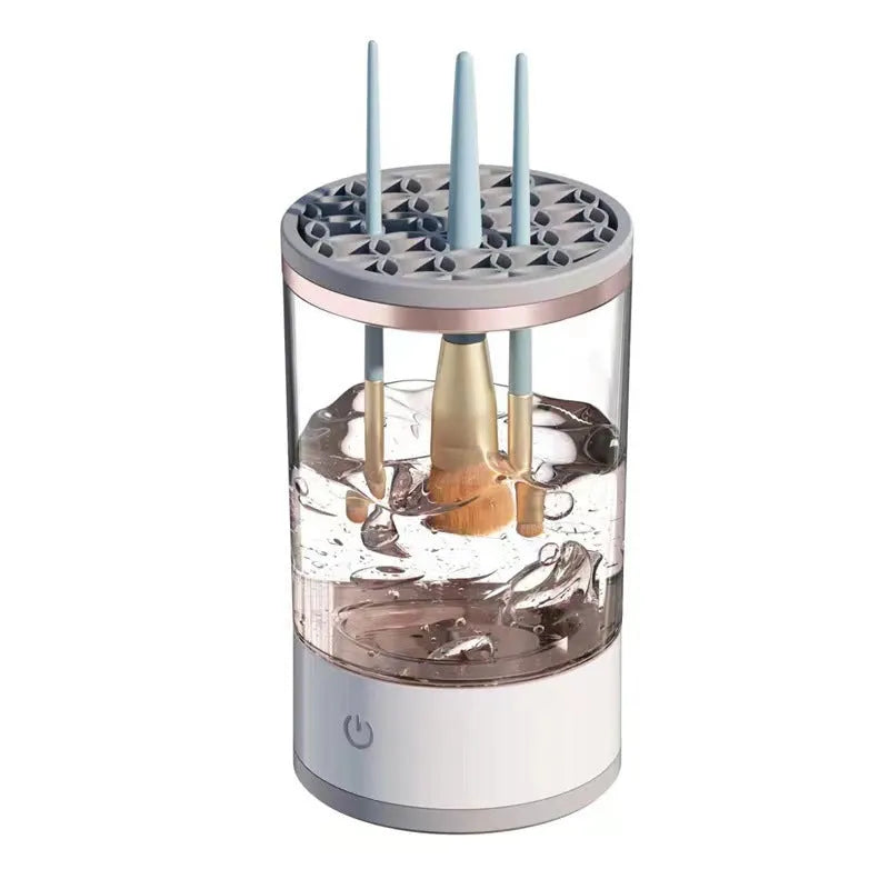 Grey and white electric makeup brush cleaner with USB charging cable on a wooden surface