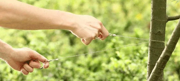 Outdoor survival wire saw with a stainless steel wire coil presented next to a small black leather carry case.
