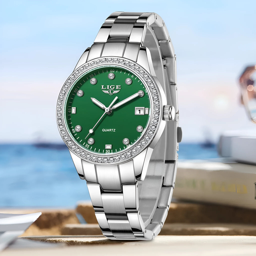 Women's silver and green quartz watch with diamond bezel, luminous hands, on a wrist.