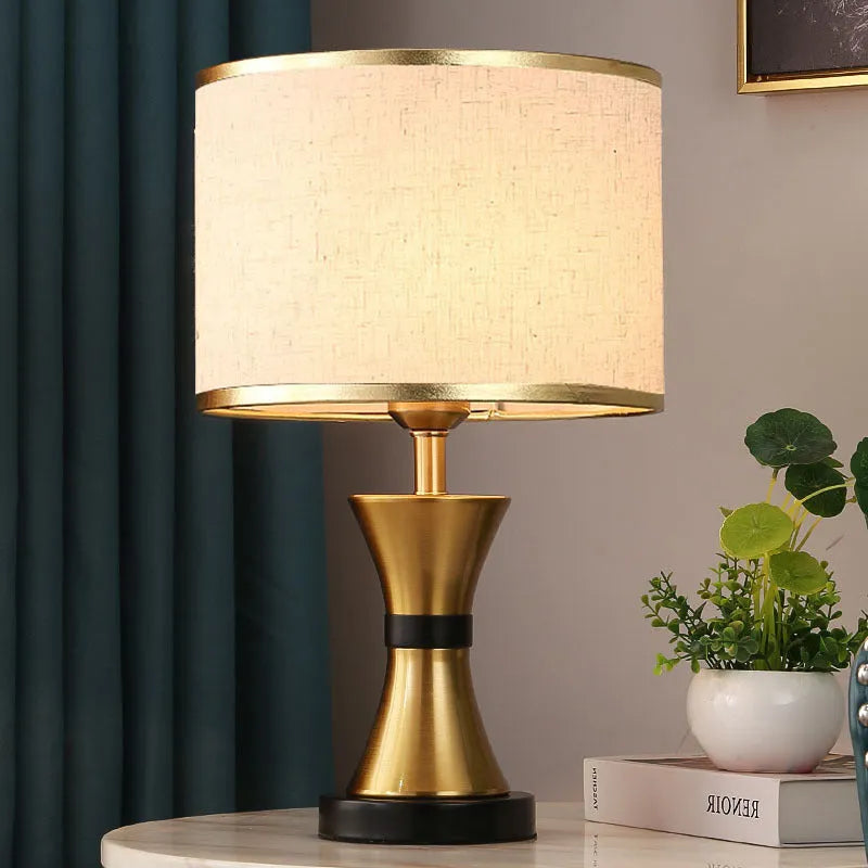 Simple iron table lamp with a fabric shade in black, gold, or white colour options.
