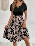 A khaki-coloured A-line women's dress with a floral print, showing regular sleeves and shoulder strap details.