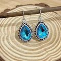 Retro style drop-shaped blue gem inlaid earrings in silver alloy, unisex jewellery on display