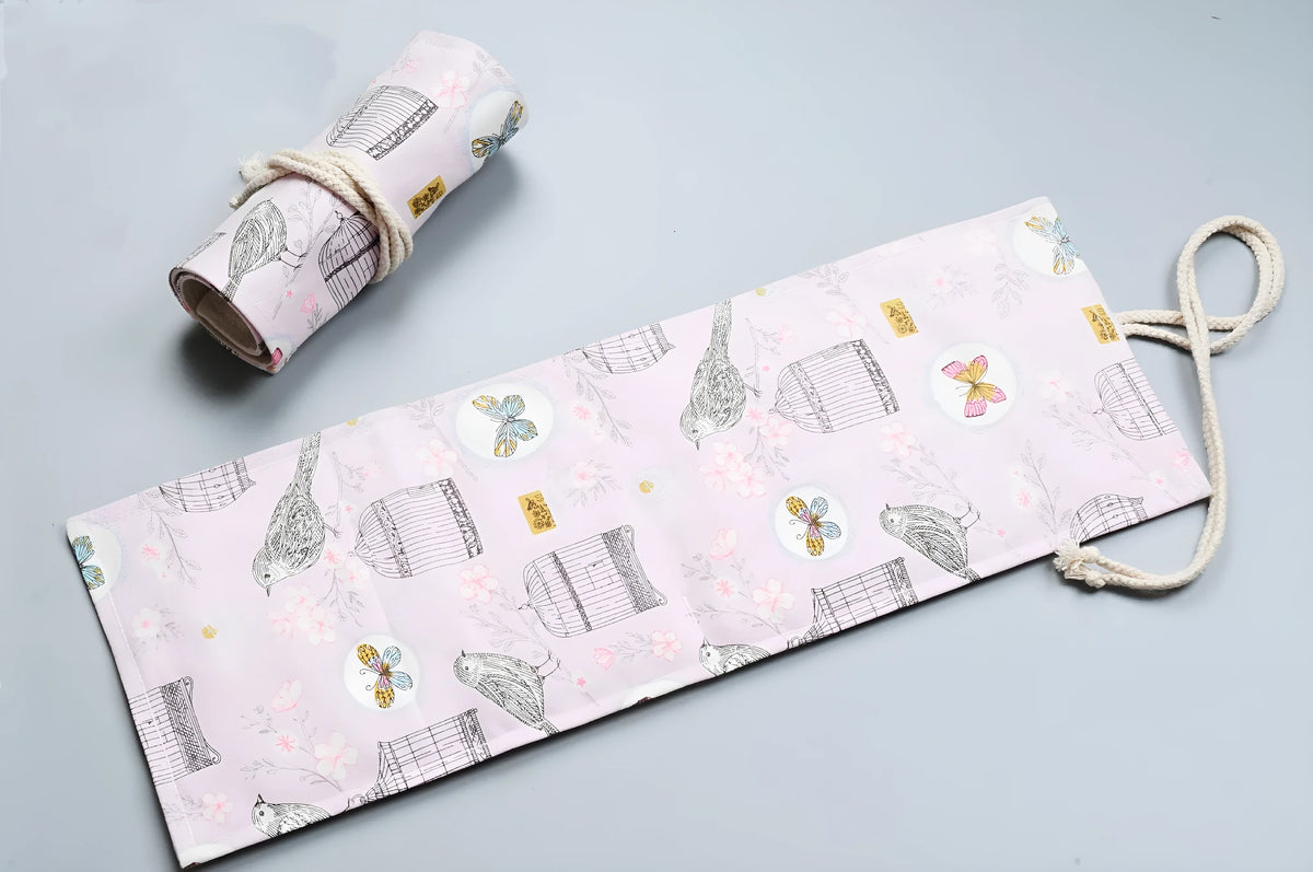 Canvas pencil wrap roll up case with multiple elastic bands holding pens and pencils, in a compact roll.