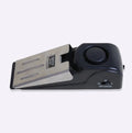 Black wedge-shaped door alarm with stainless steel cover and sensitivity controls