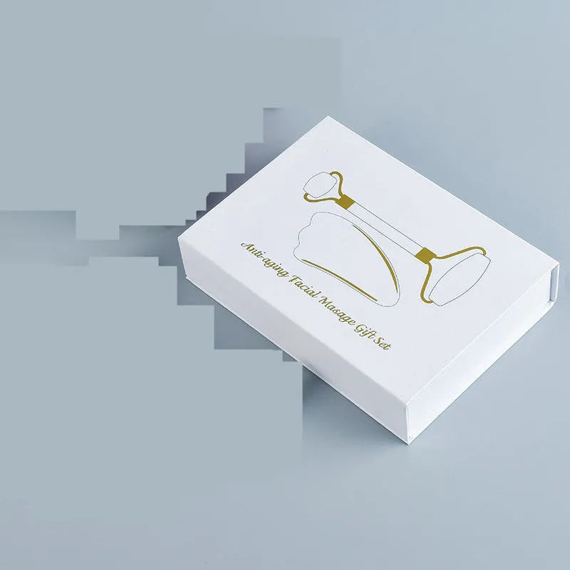 White jade double-headed facial roller and matching gua sha board set on a plain background.
