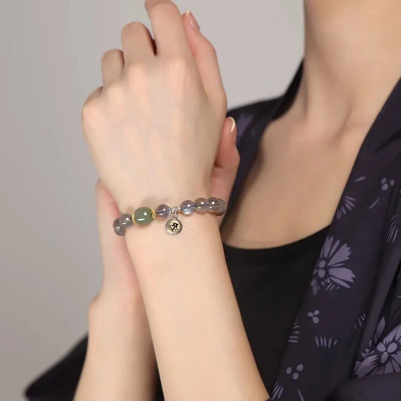 Close-up of an 8mm Moonstone crystal bracelet showing a detailed Thousand-Hand Kwan-yin mouse design.