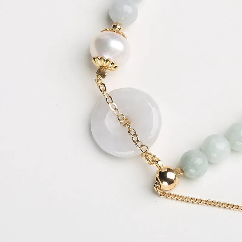 Jade and pearl bracelet with geometric pendant and peace buckle charm on wrist