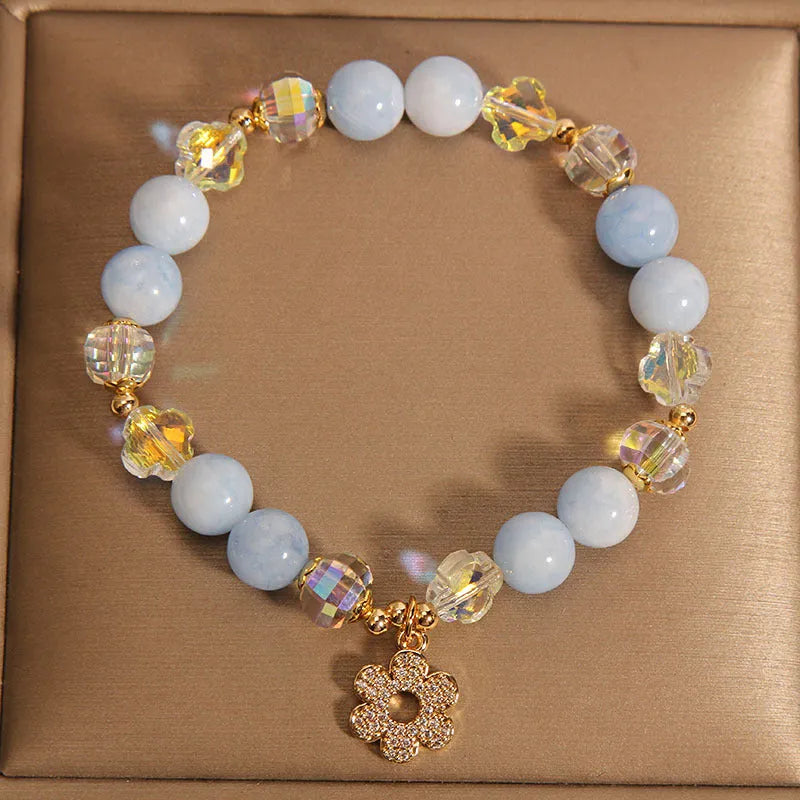 Women's aquamarine crystal bracelet with a four-leaf clover charm and small pearl accent.
