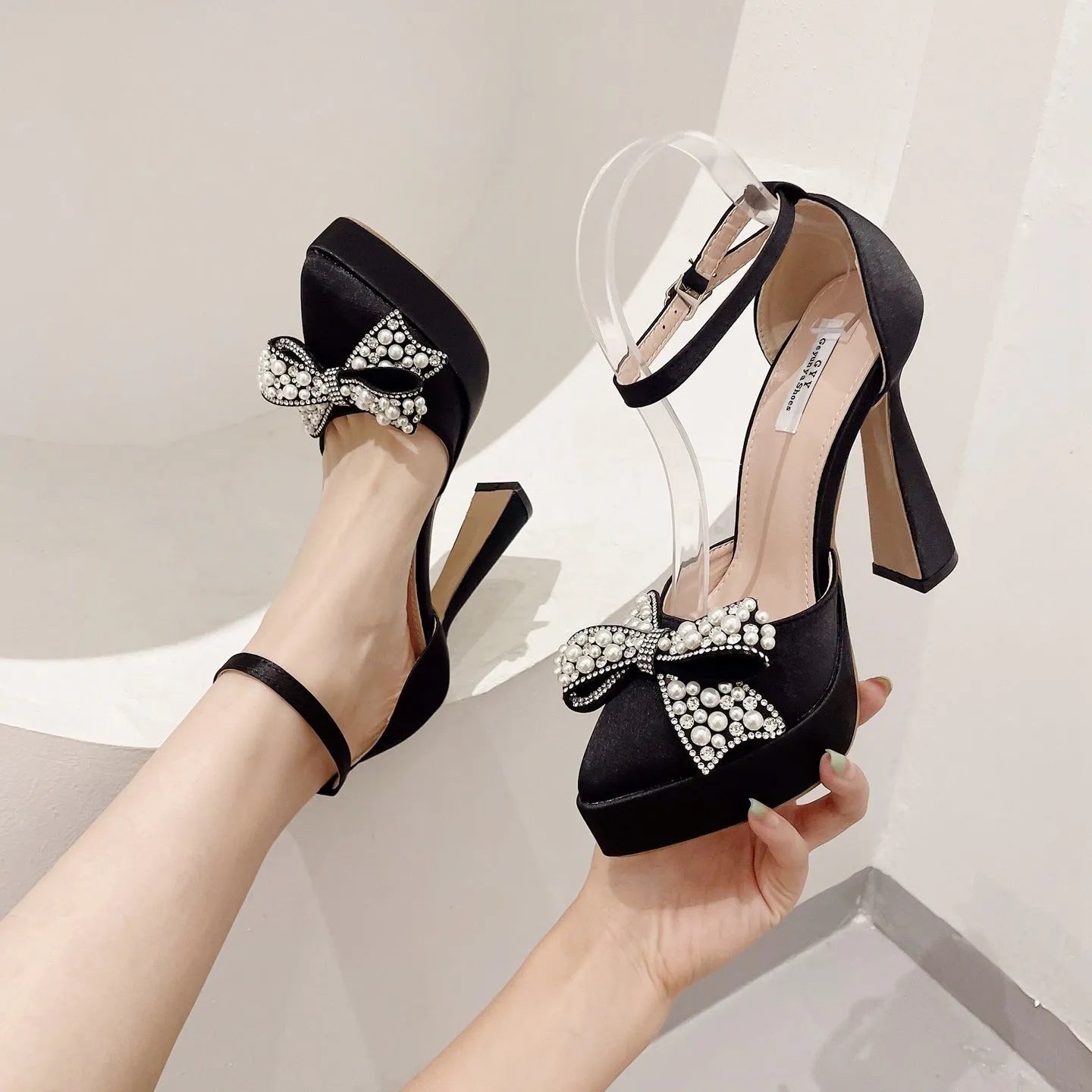 Women's black pointed-toe pumps with bow detail and satin upper on rubber sole