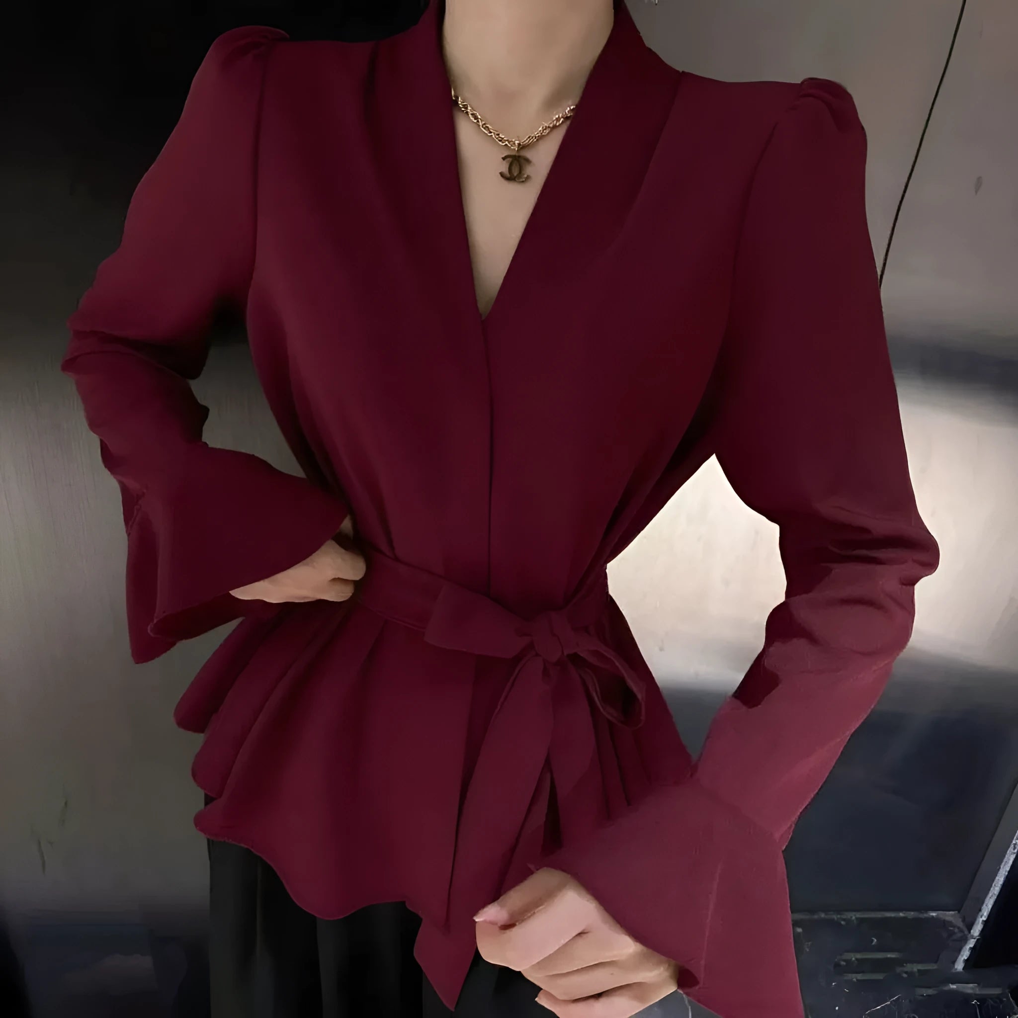 Women's black French-style shirt with an irregular collar and long bell sleeves laid flat.