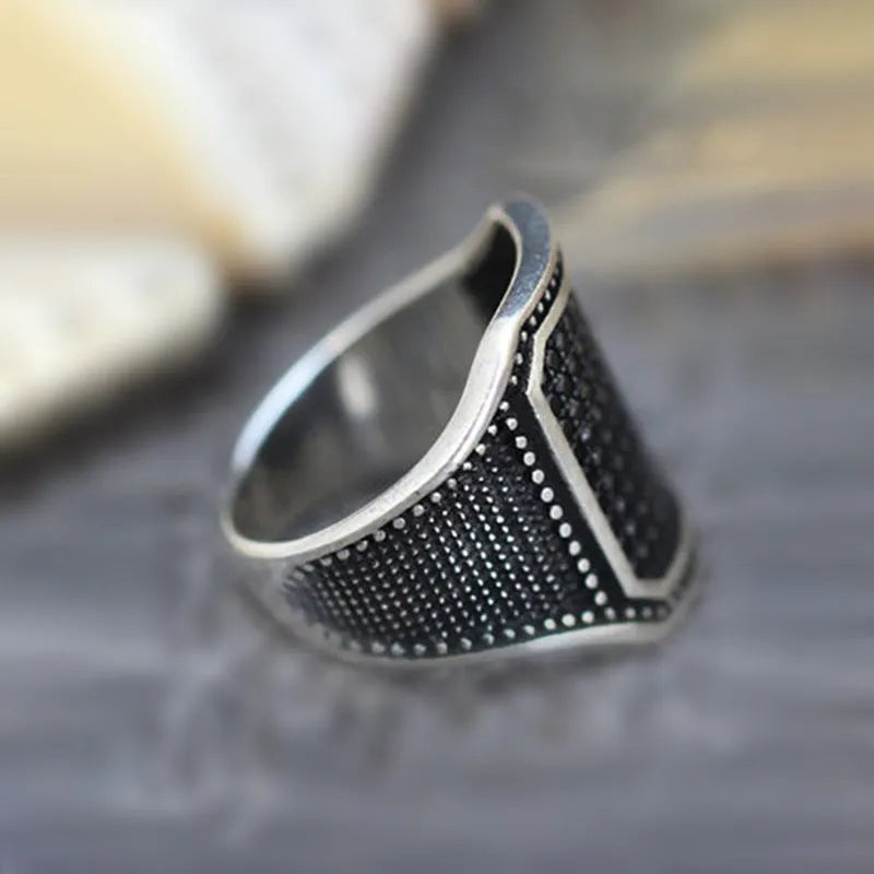 Black alloy ring with copper inlay detail and a central zircon stone on a finger.