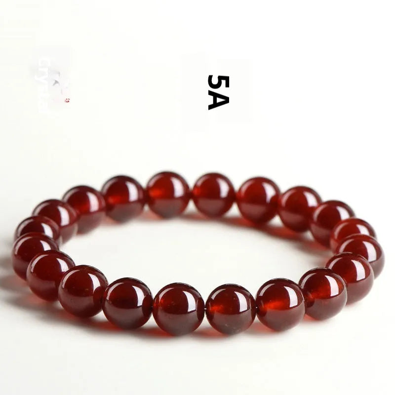 Natural orange red garnet ball crystal bracelet with a silver ruyi charm on a white background.