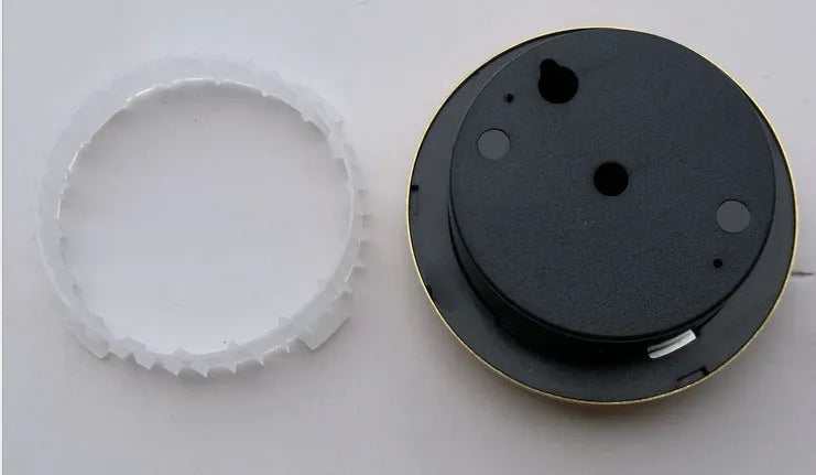 Analogue thermometer and hygrometer with aluminium ring and dial on a white wall.