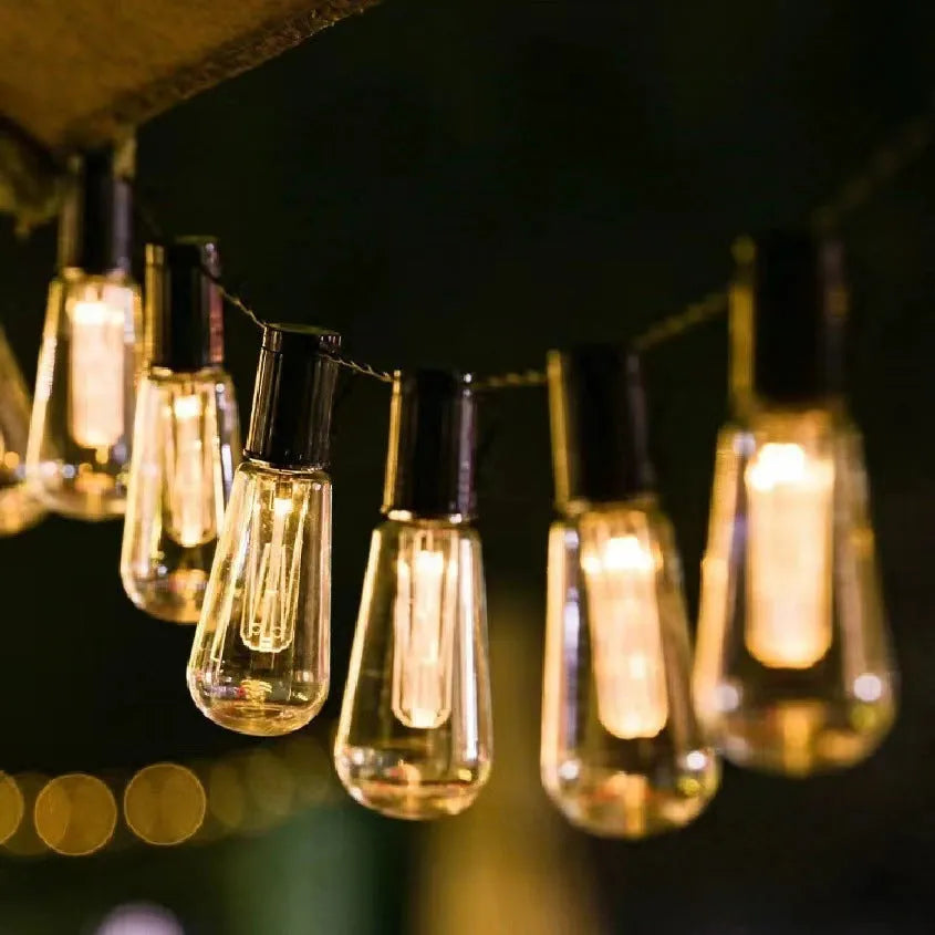 Retro solar outdoor string lights with infusion bottle shape bulbs in garden setting