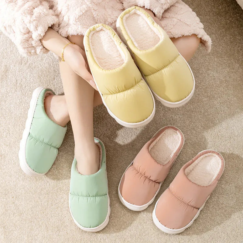 A pair of blue down cotton slippers with a thick sole, artificial leather upper, and plush lining for indoor winter wear.