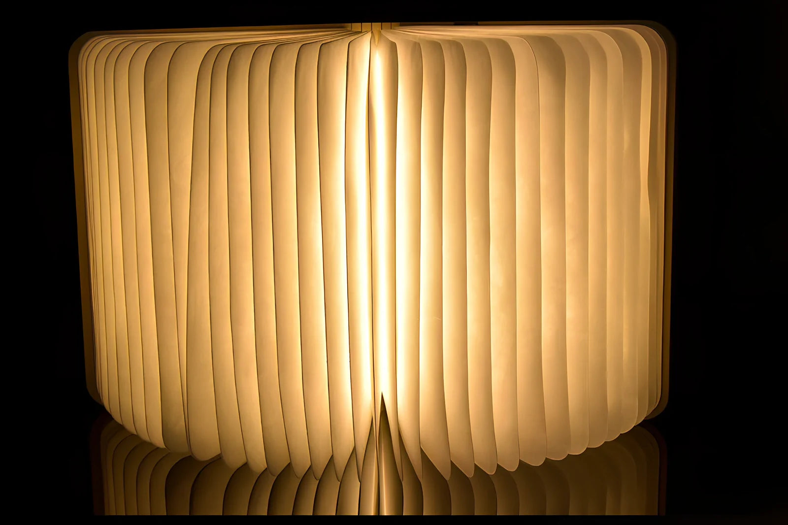 Wooden folding LED book light in walnut finish, open to 360 degrees showing warm white illumination on Tyvek pages, 21.5cm size