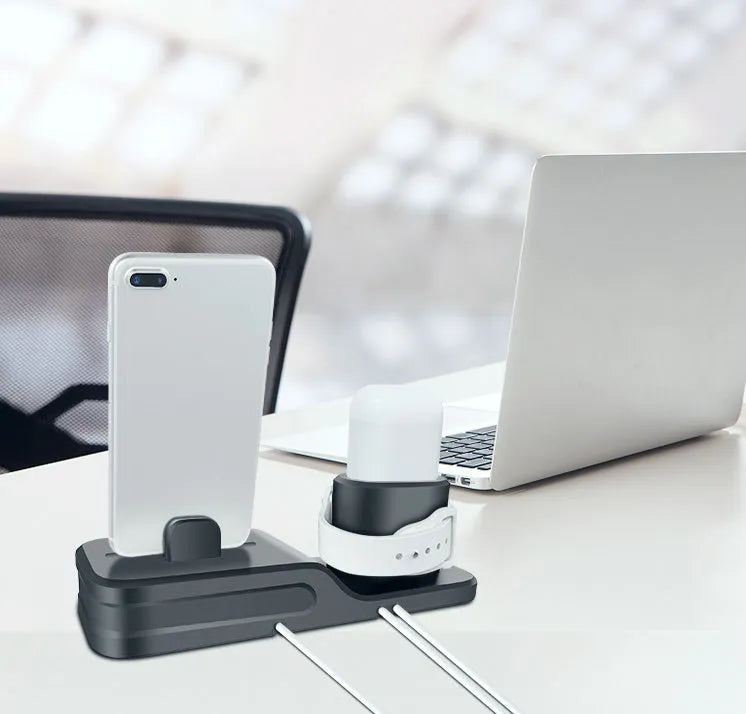 Black geometric 3-in-1 charging stand for Apple iPhone, Watch, and AirPods on a desk.