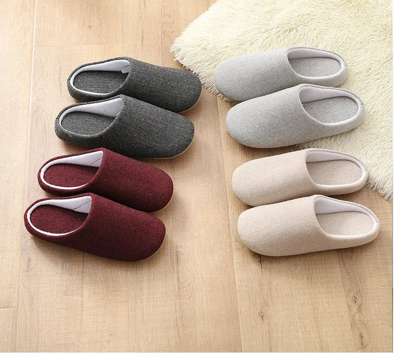 Men's black cotton indoor slippers with soft anti-skid sole on a wooden floor