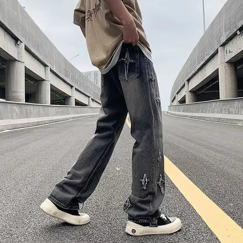 Men's loose denim trousers in black, straight-leg style with zipper fly, lying flat on a surface