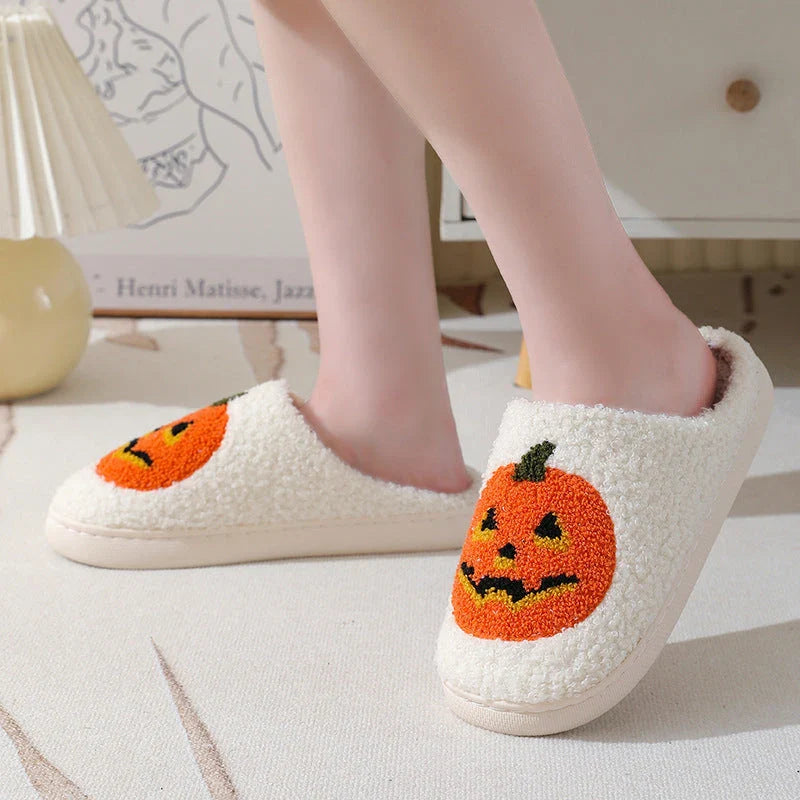 Cozy Halloween-themed pumpkin slippers in white and black colors, featuring soft suede uppers and durable rubber soles for indoor wear