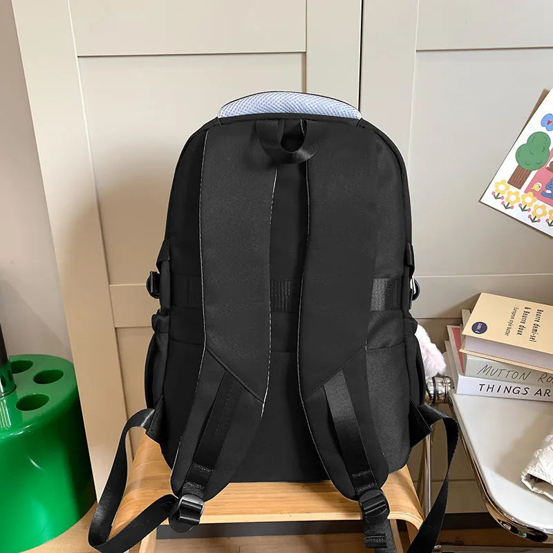 Large black nylon school backpack with curved straps, shown with and without a decorative pendant.