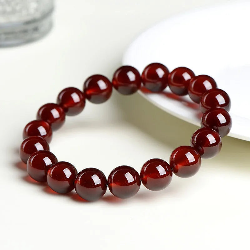 Natural orange red garnet ball crystal bracelet with a silver ruyi charm on a white background.