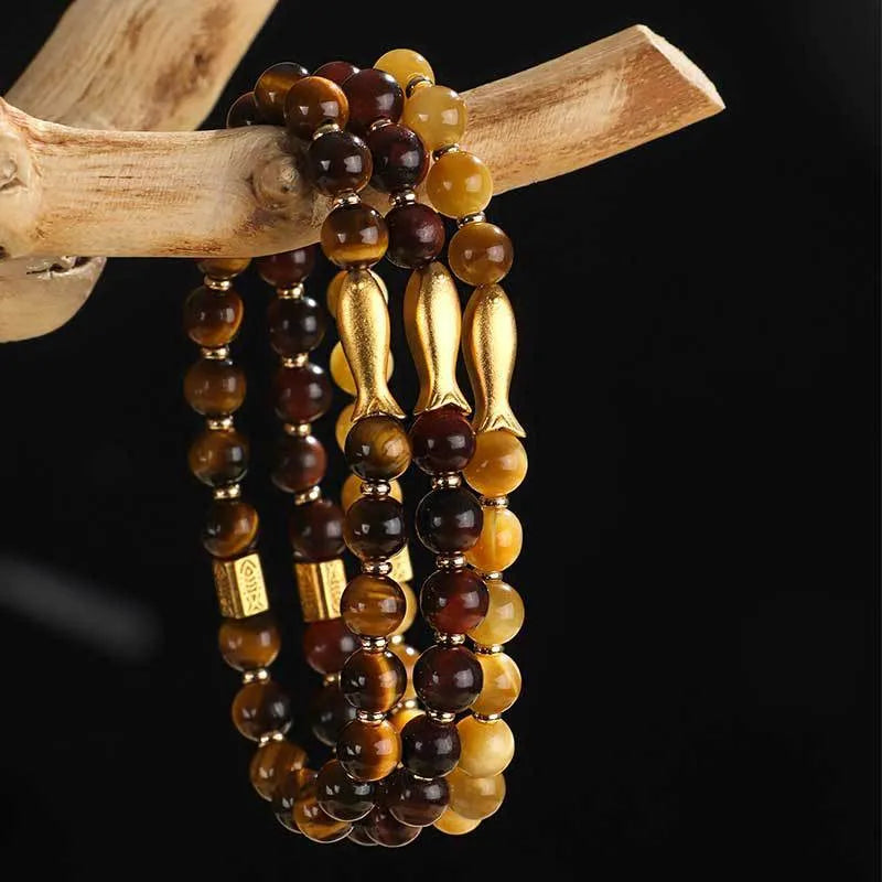 Women's tiger eye bracelet with small gold fish charm on adjustable band