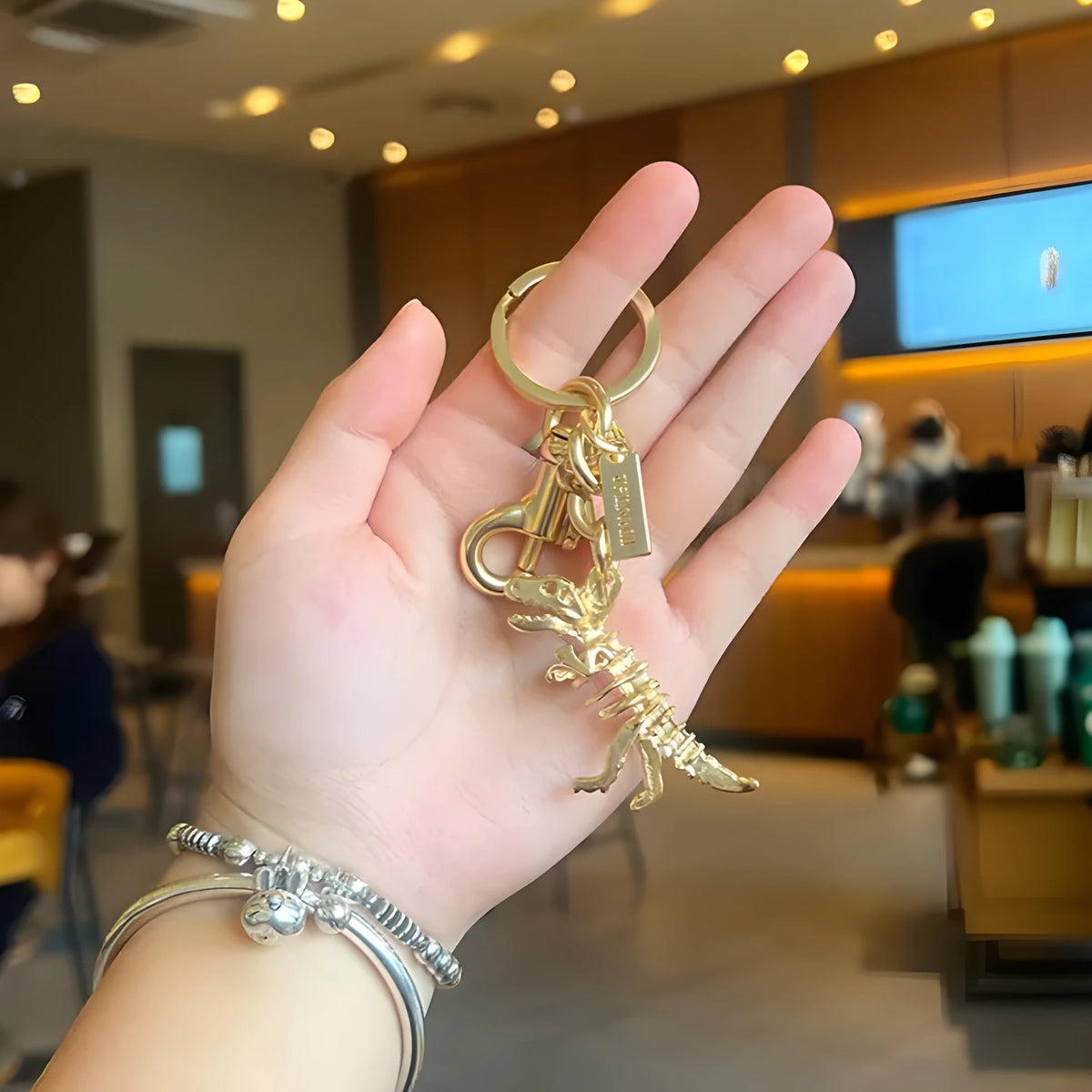 Golden bone dragon zinc alloy dinosaur keychain on a neutral background, showing retro animal pattern