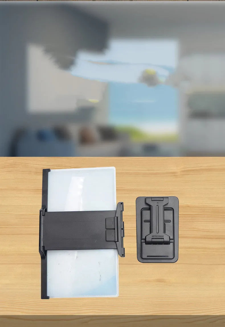 Black folding mobile phone screen magnifier and detachable holder on a desktop.