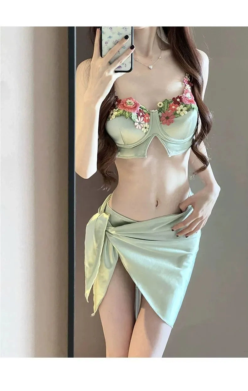 Green women's three-piece bikini set showing triangle top, briefs, and removable skirt laid flat.