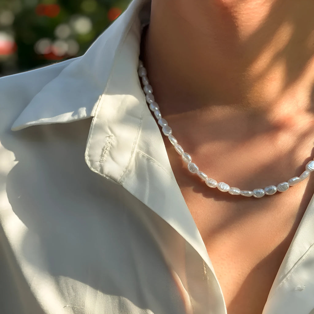 Men's white U-shaped pearl necklace with mother-of-pearl pendant on a pearl chain.