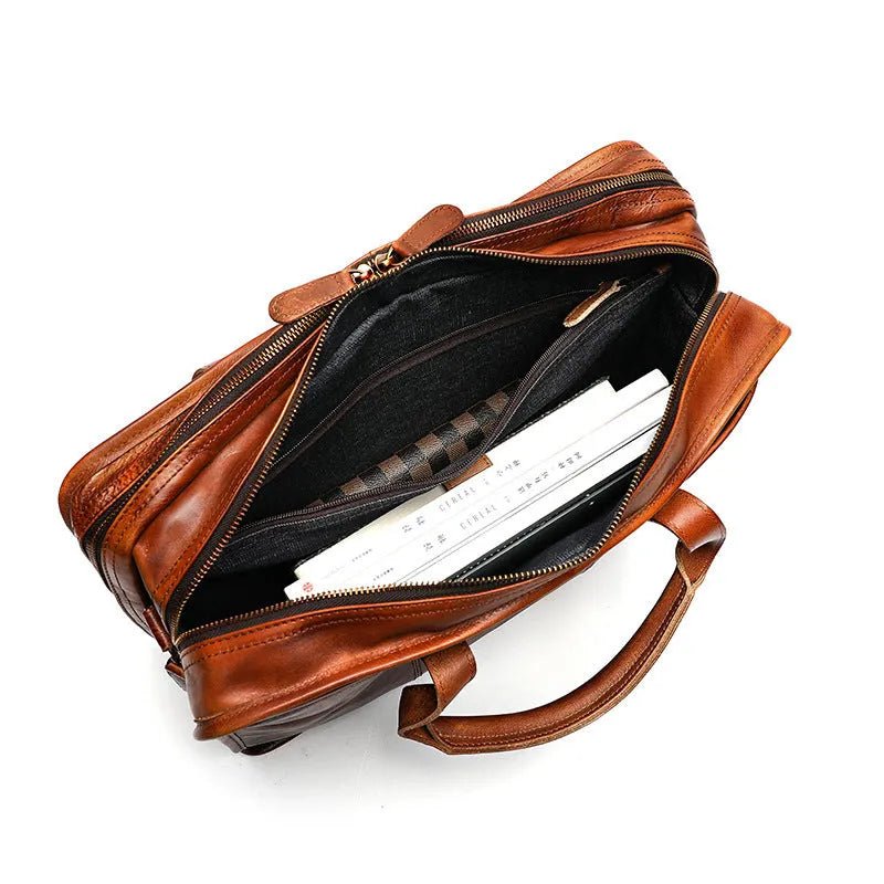Vintage brown leather men's briefcase showing internal laptop and camera compartments.
