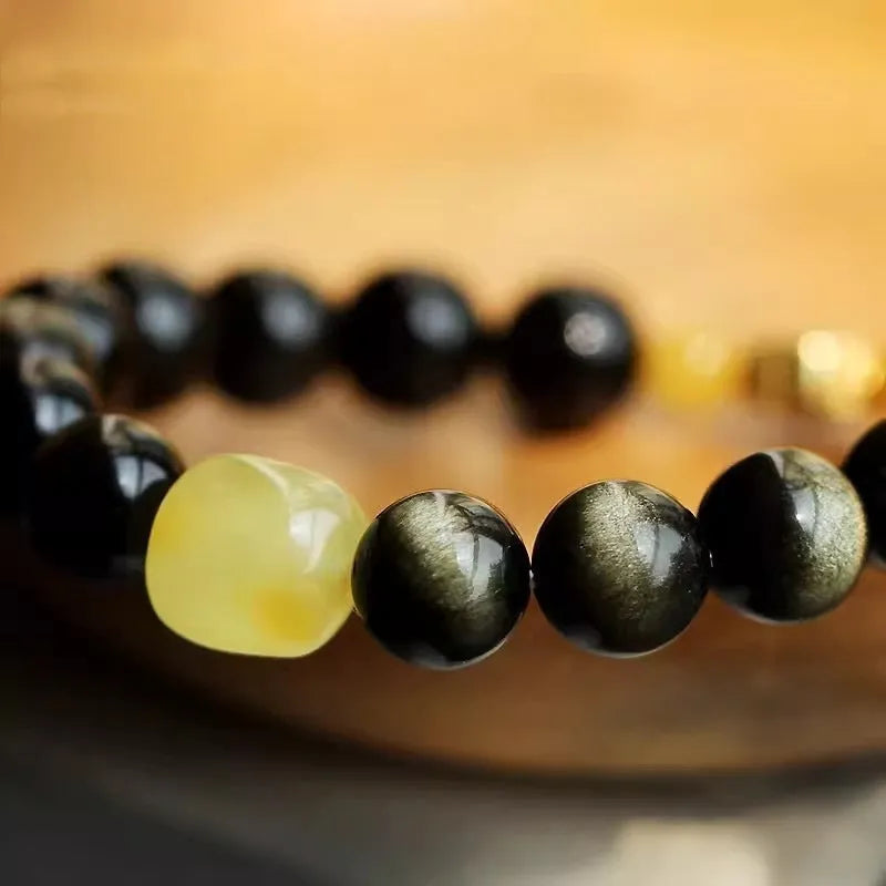 Golden obsidian bracelet with carved zodiac symbols on geometric beads
