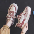 Pink and white low top women's sneakers with a rubber sole and height increasing feature.